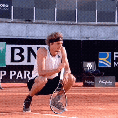 Man Squatting Holding Tennis Racquet Near BN Logo GIF