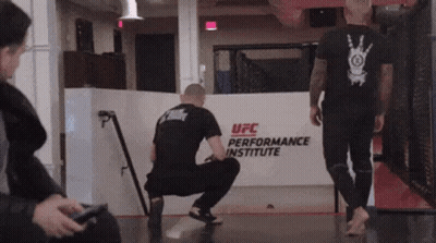 Man Squatting In Front Of UFC Performance Institute Sign GIF