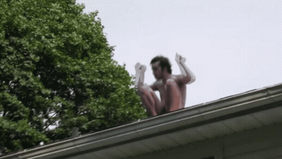 Man Squatting On Roof With Arms Up GIF
