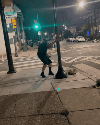 Man Squatting On Sidewalk At Stevens Ave GIF