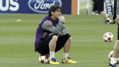 Man Squatting On Soccer Ball In Front Of Ford Sign GIF