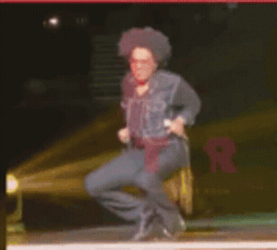 Man Squatting On Stage With Microphone GIF