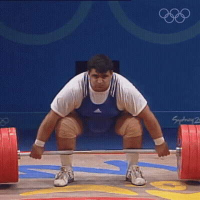 Man Squatting With Barbell In Front Of Sydney 2002 Sign GIF
