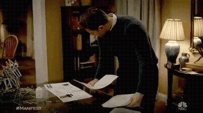 Man Standing At Desk Holding Papers GIF