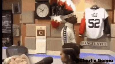 Man Standing At Microphone With Clock And Jersey On Wall GIF