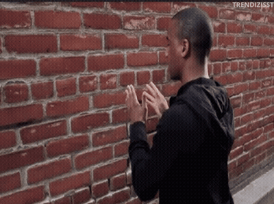 Man Standing Before Brick Wall With Hashtag Trendizisst GIF