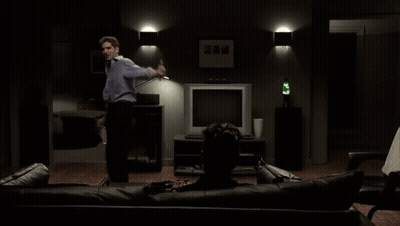 Man Standing Beside Man Sitting On Couch Watching TV GIF