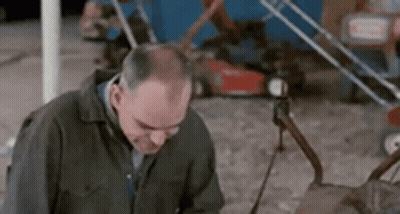 Man Standing By Lawn Mower Looking Down GIF