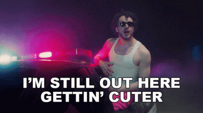 Man Standing By Police Car Saying I'm Still Out Here Gettin' Cuter GIF