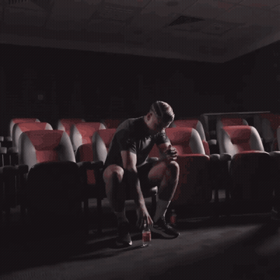 Man Standing In Auditorium Holding Bottle GIF
