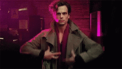 Man Standing In Dark Room Holding Jacket And Sword GIF