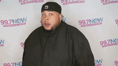 Man Standing In Front Of 99.7 Now Wall GIF