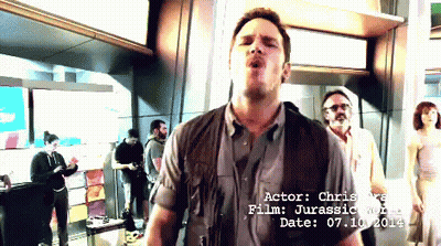 Man Standing In Front Of Actor Chris Rea Jurassic World Sign GIF
