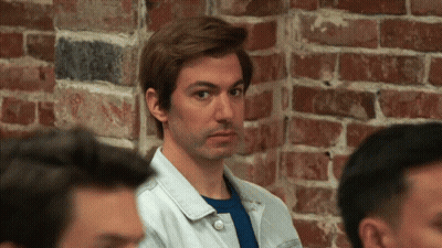 Man Standing In Front Of Brick Wall Looking At Camera GIF