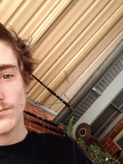 Man Standing In Front Of Brick Wall With Fishing Rod GIF