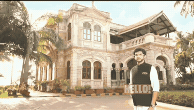 Man Standing In Front Of Building Saying Hello GIF