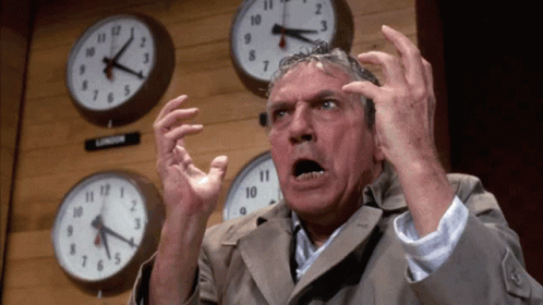 Man Standing In Front Of Clocks Including London GIF
