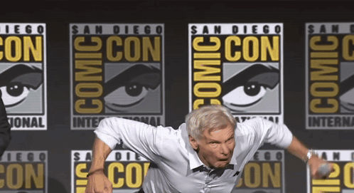 Man Standing In Front Of Comic Con Logo GIF