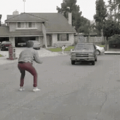 Man Standing In Front Of Driving Car GIF