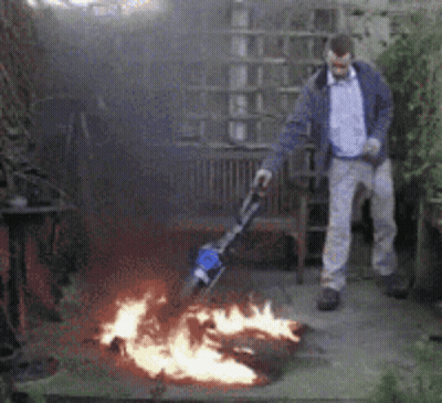 Man Standing In Front Of Fire With Vacuum GIF