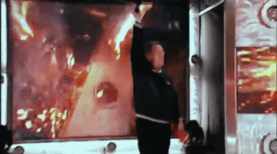 Man Standing In Front Of Screen With Flames GIF