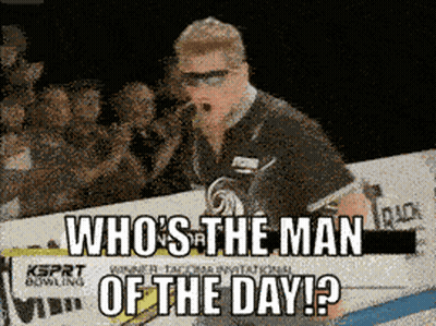 Man Standing In Front Of Sign Saying Who's The Man Of The Day GIF