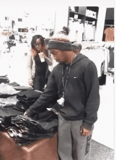 Man Standing In Front Of Stack Of Clothes GIF