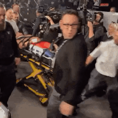 Man Standing In Front Of Stretcher With Man On It GIF