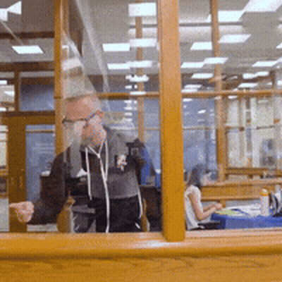 Man Standing In Front Of Window With Woman At Desk GIF