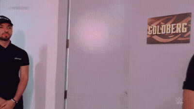 Man Standing In Room With Goldberg Sign GIF