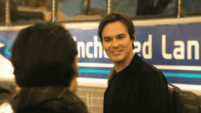 Man Standing Next To Another Man In Front Of Bus GIF