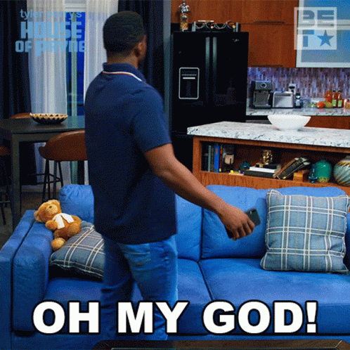 Man Standing Next To Blue Couch Saying Oh My God GIF