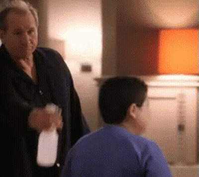 Man Standing Next To Boy In Blue Shirt Holding Milk GIF
