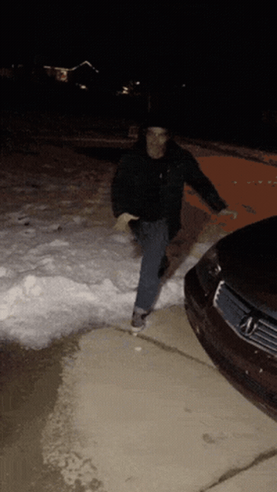 Man Standing Next to Car in Snow at Night