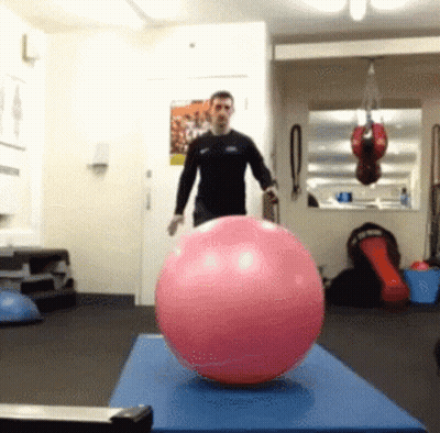 Man Standing Next To Pink Ball On Blue Mat GIF