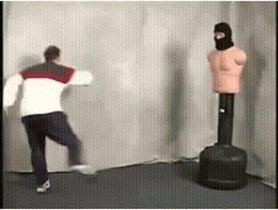 Man Standing Next To Punching Bag And Mannequin Wearing Mask GIF