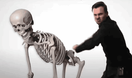 Man Standing Next To Skeleton With Skull GIF