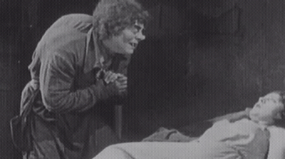 Man Standing Next To Woman Laying In Bed GIF