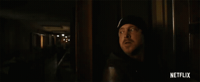 Man Standing Next To Yellow Netflix Tape In Dark Room GIF