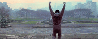 Man Standing On Ledge With Arms Up GIF