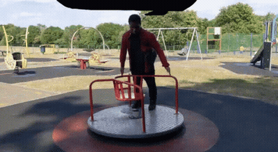 Man Standing On Merry Go Round In Park GIF