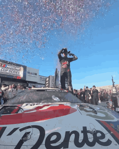 Man Standing On NASCAR Car With Confetti GIF