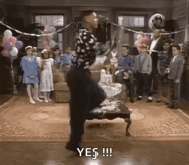 Man Standing On One Leg In Front Of Microphone In Living Room With Balloons GIF