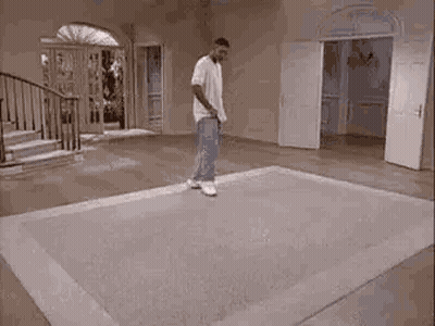 Hombre de pie sobre alfombra sosteniendo raqueta de tenis GIF