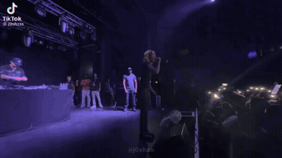 Man Standing On Stage In Front Of Microphone And Crowd GIF