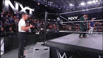 Man Standing On Stage In Front Of NXT Sign GIF