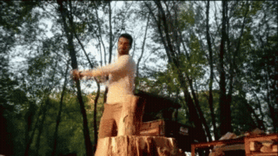 Man Standing On Stump In Woods GIF