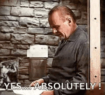 Man Standing With Paper In Front Of Brick Wall GIF