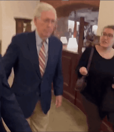 Man Suit Tie Walking Hallway Woman Behind GIF