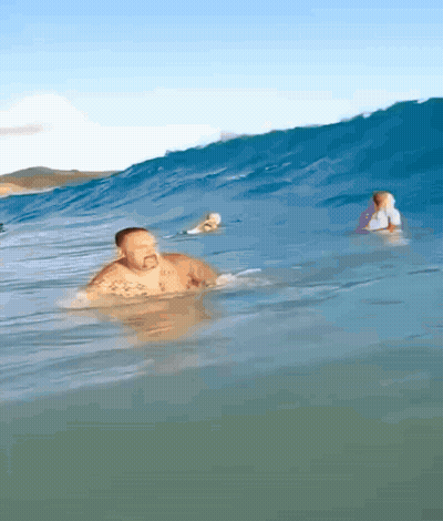 Man Swimming While Surfer Rides Wave GIF